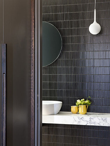 warm and moody bathroom with stacked tile behind the sink