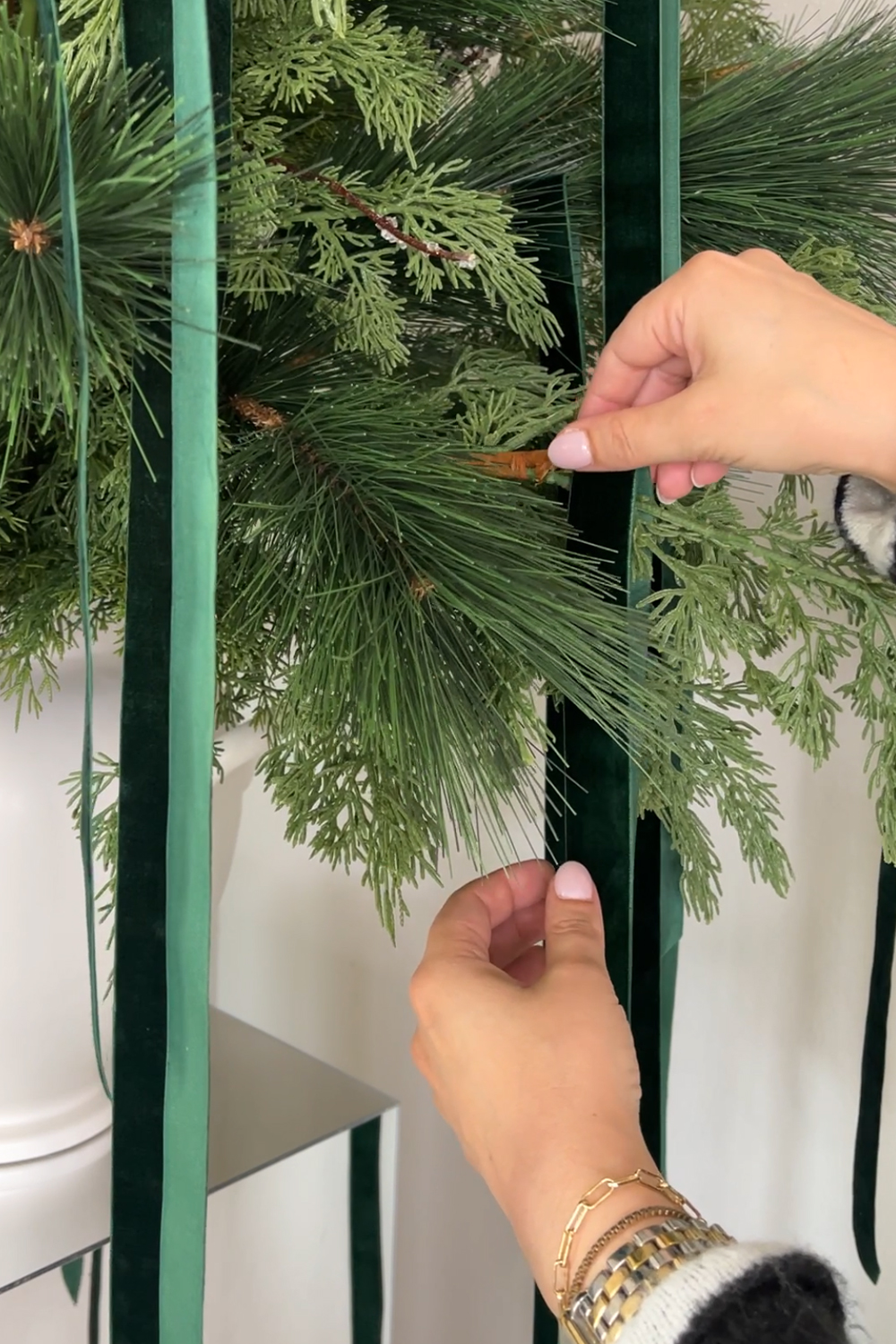 Learn how to design a modern Christmas floral arrangement with cedar and pine faux greenery and branches, velvet ribbon, and mirrored pedestals. Add a touch of elegance and sparkle to your holiday decor!